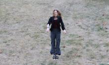 Samantha jumping in a field of scraggly grass