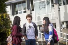 three students talking in the quad