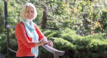 Dr. Cynthia-Lou Coleman leans against a railing near VIU's koi pond with sun hitting her hair.