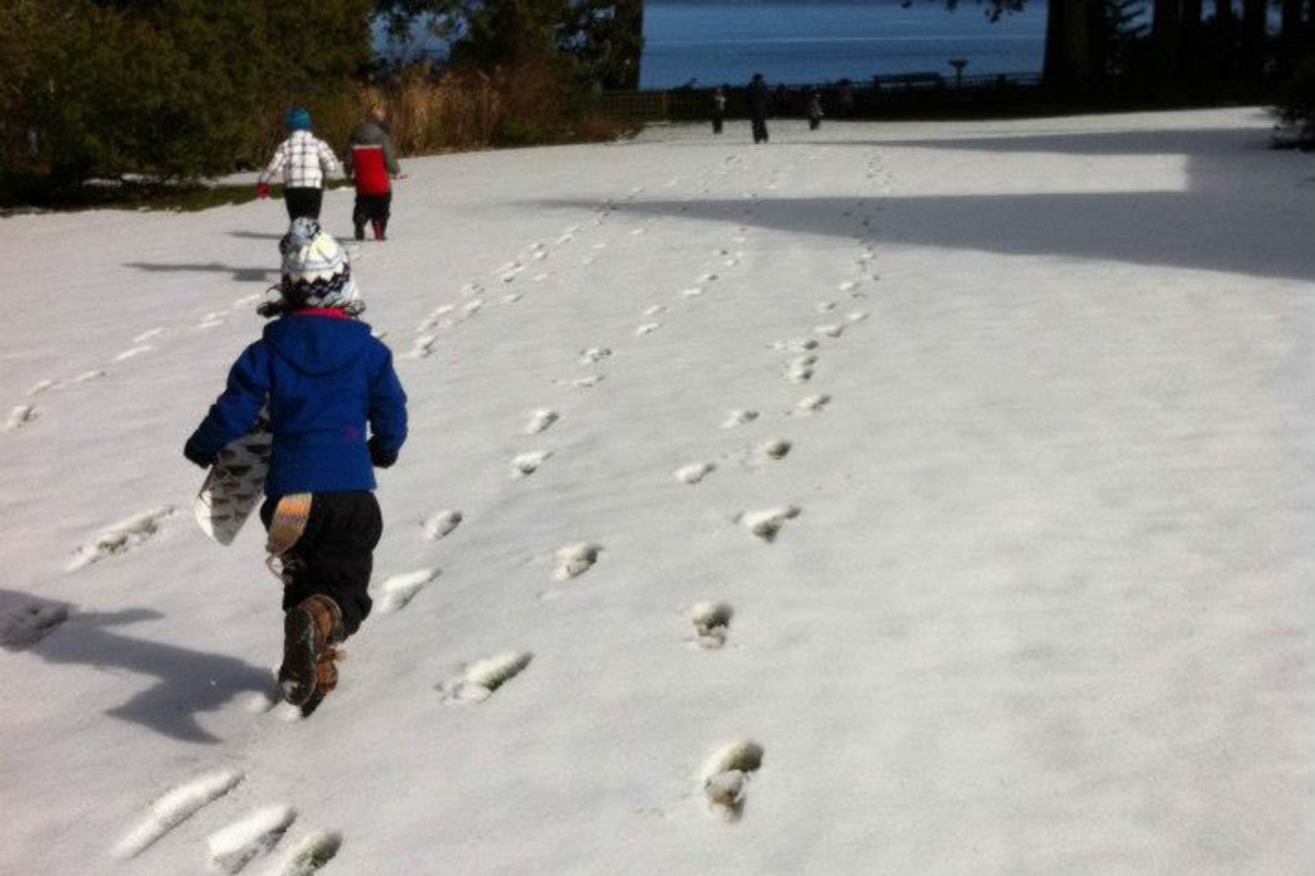 Children running across a snowy lawn