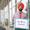 Harpreet outside the Centre for Health and Science holding a sign that reads We love our donors! 